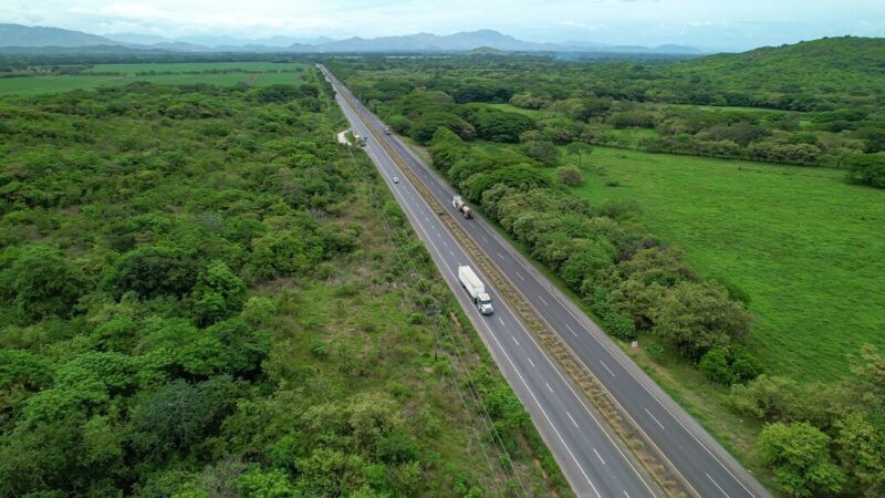 Highway cutting through green landscape with trucks traveling across Panama countryside