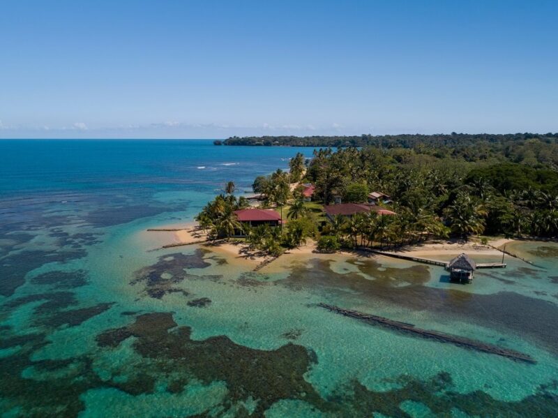 Small tropical island with palm trees and clear turquoise water along Panama coast